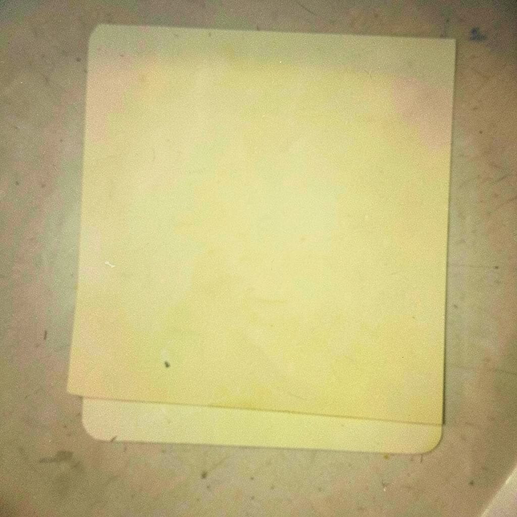 A warm, grainy film photograph of a neatly arranged flat-lay of clothing labels and small fashion accessories in soft yellow and indigo tones, cozy and personal mood